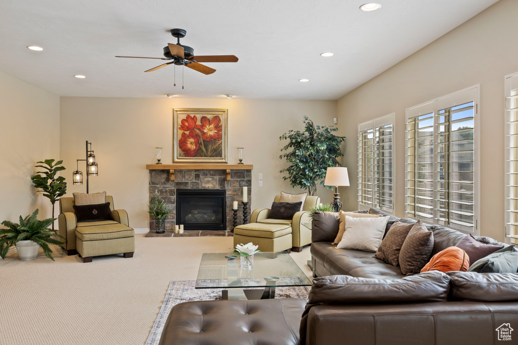 Living area with ceiling fan, carpet, a stone fireplace, and recessed lighting