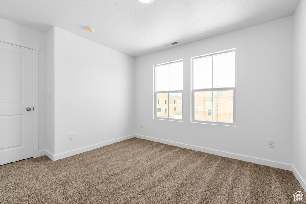 Empty room featuring baseboards, visible vents, and carpet