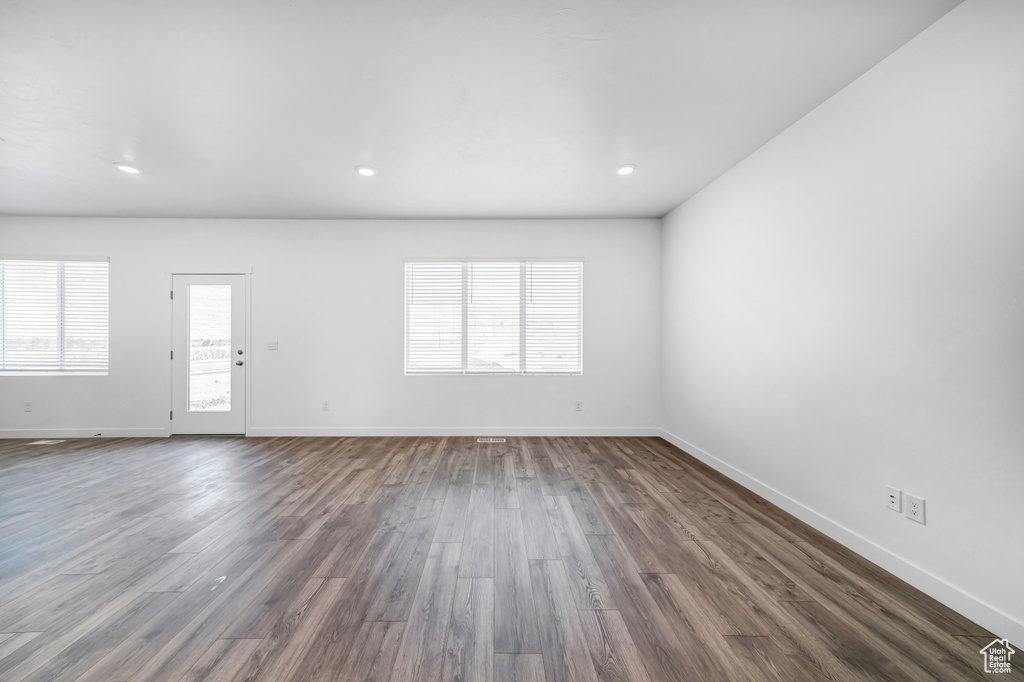 Unfurnished living room featuring baseboards, recessed lighting, and dark wood-style flooring