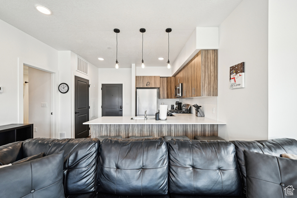 Kitchen with open floor plan, a peninsula, brown cabinets, and stainless steel appliances
