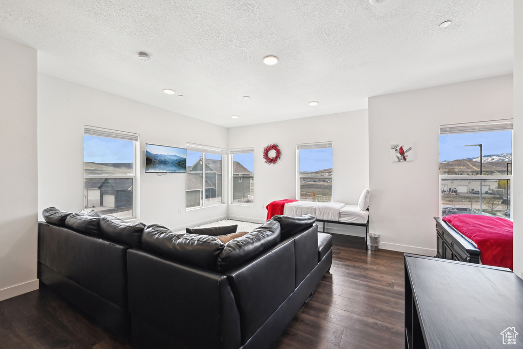 Living area with recessed lighting, baseboards, dark wood-style flooring, and a textured ceiling