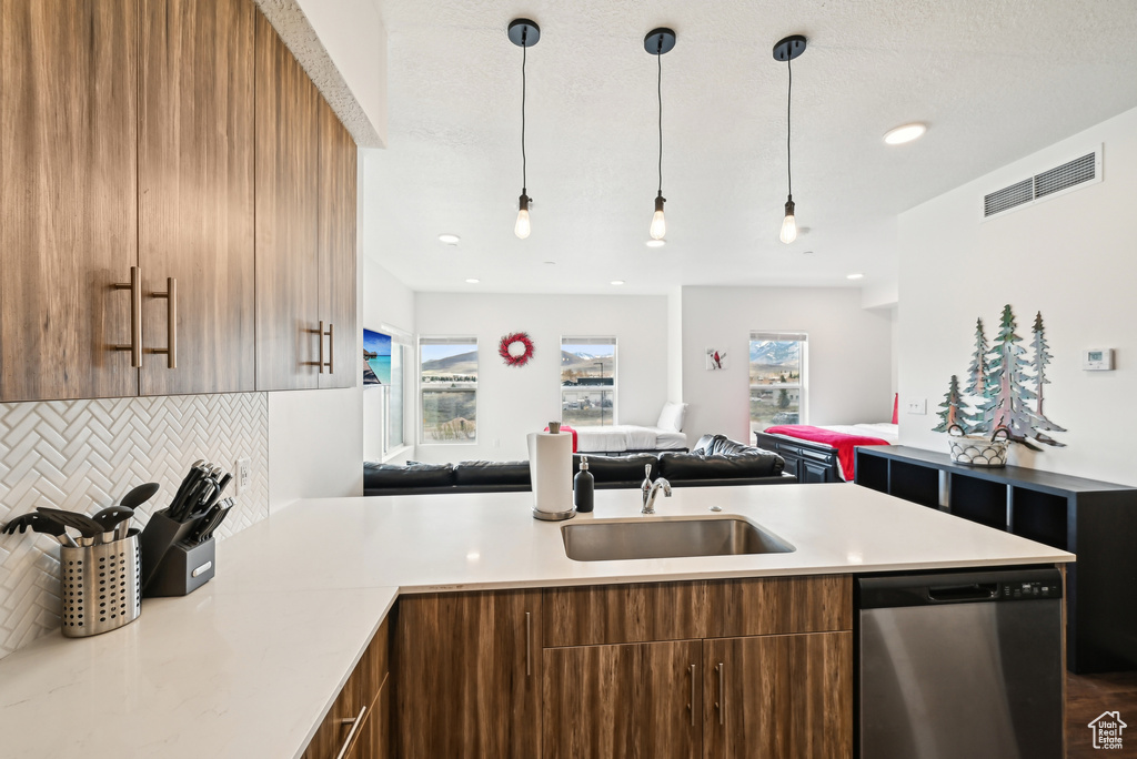 Kitchen featuring a sink, dishwasher, light countertops, decorative backsplash, and visible vents