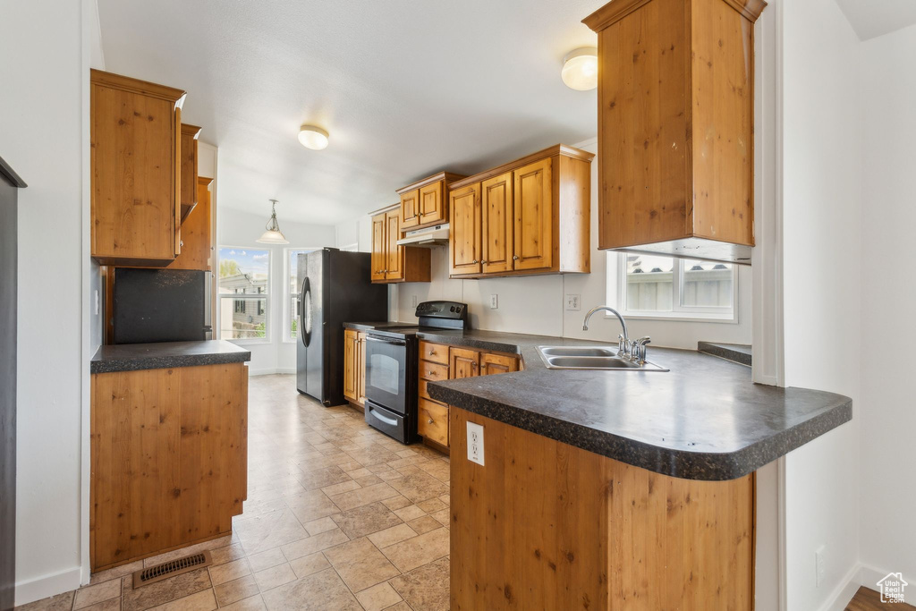 Kitchen with dark countertops, a sink, a peninsula, under cabinet range hood, and black appliances
