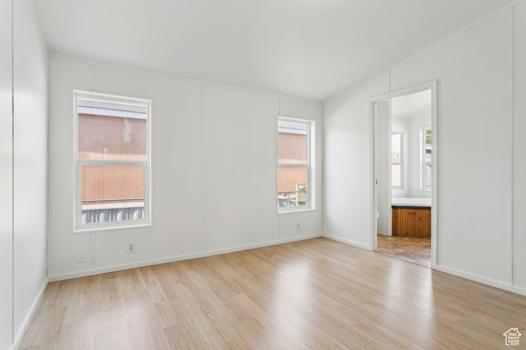 Unfurnished bedroom featuring ensuite bathroom, baseboards, and wood finished floors