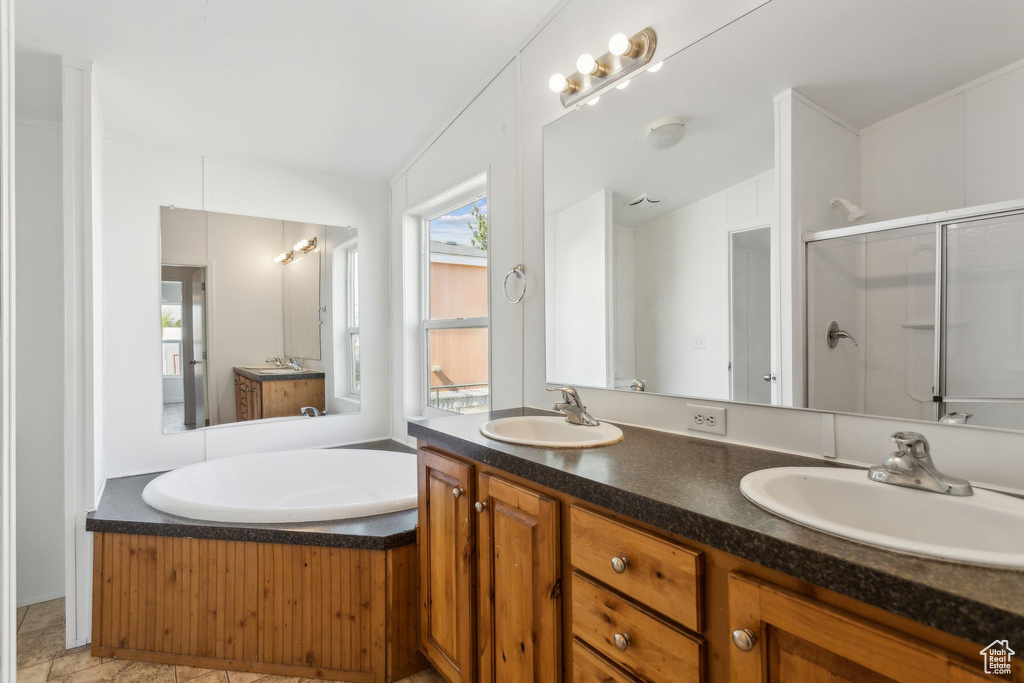 Full bath featuring a sink, double vanity, a stall shower, and a garden tub