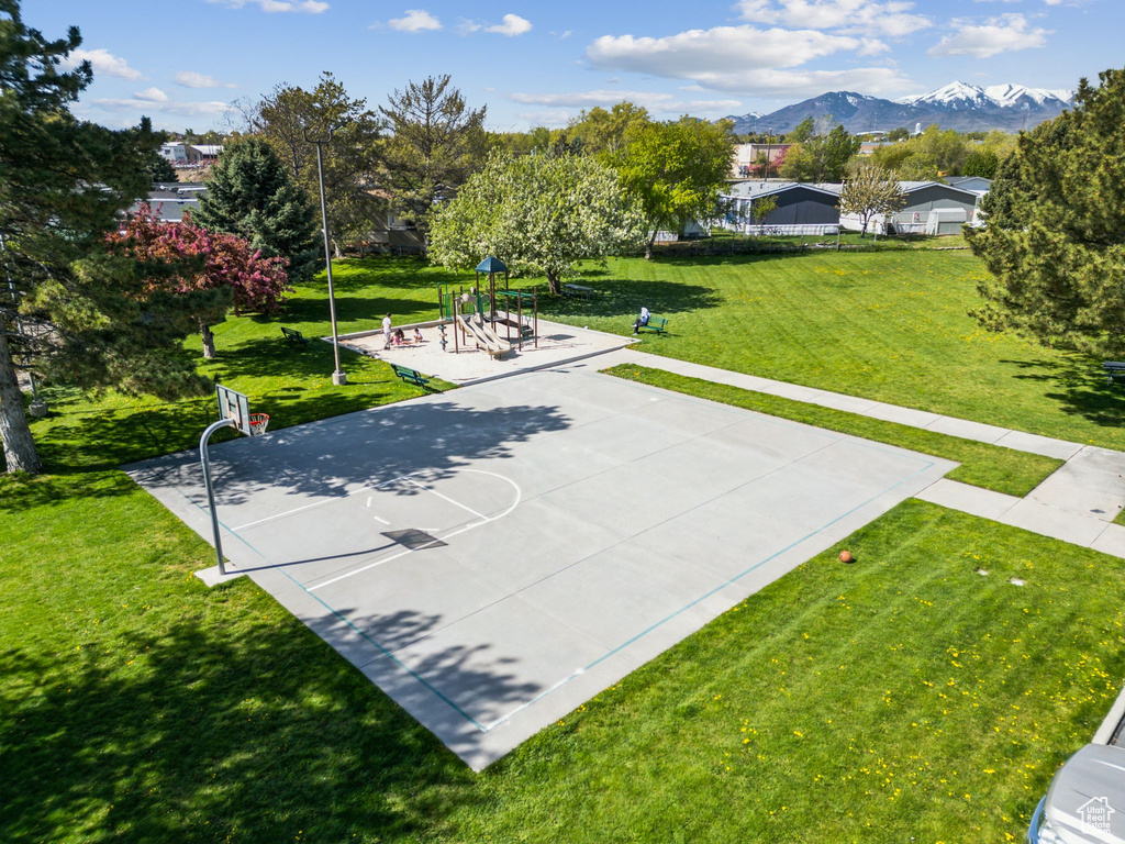 View of sport court featuring a lawn, a mountain view, community basketball court, and playground community