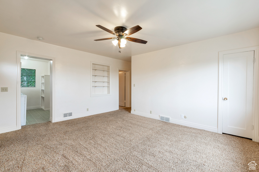 Unfurnished bedroom with carpet flooring, baseboards, visible vents, and ensuite bath