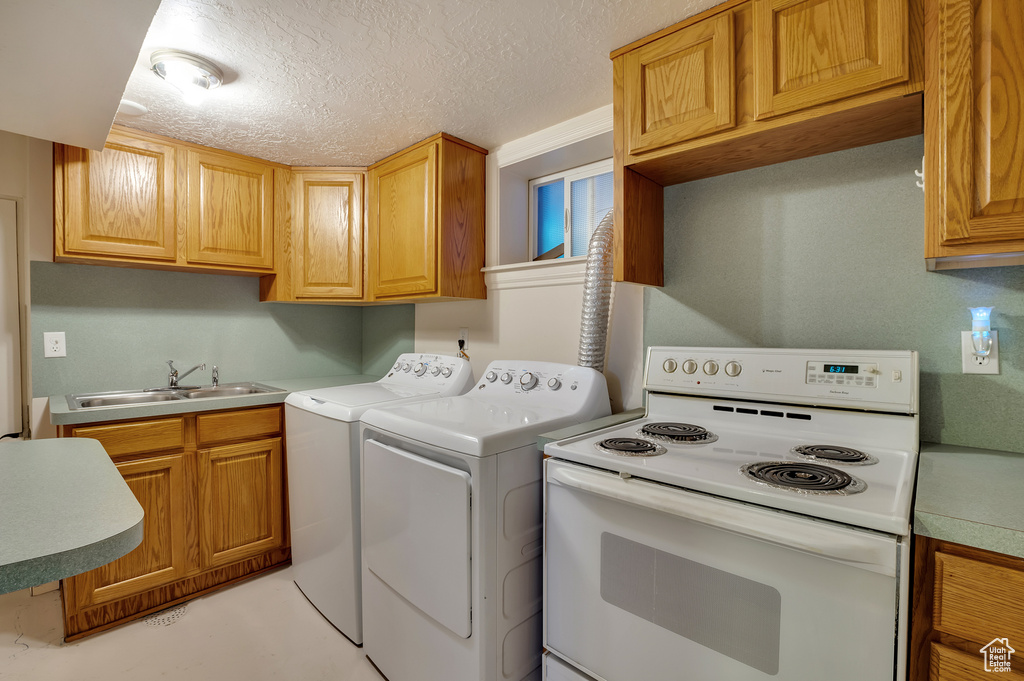 Washroom featuring laundry area, a sink, a textured ceiling, and washer and dryer