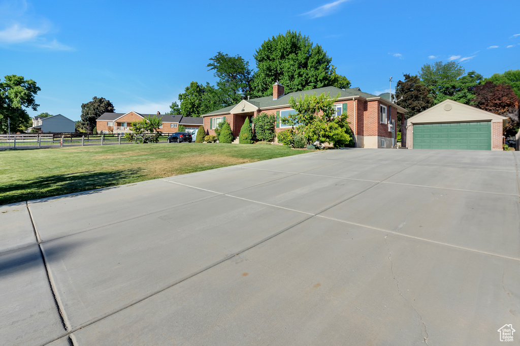 Ranch-style house with a chimney, a garage, brick siding, fence, and a front lawn