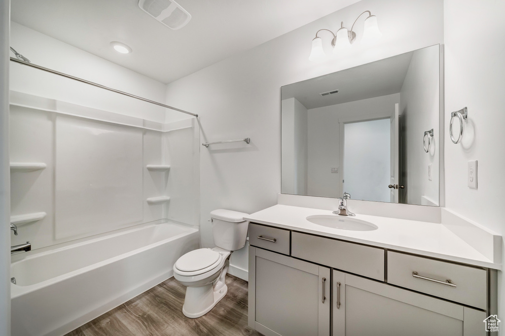 Bathroom with visible vents, wood finished floors, vanity, toilet, and shower / bathtub combination