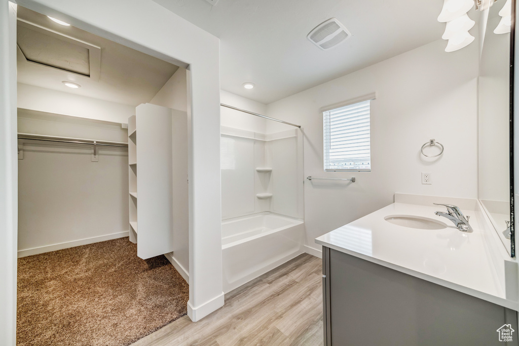 Full bath featuring vanity, baseboards, shower / washtub combination, wood finished floors, and a spacious closet