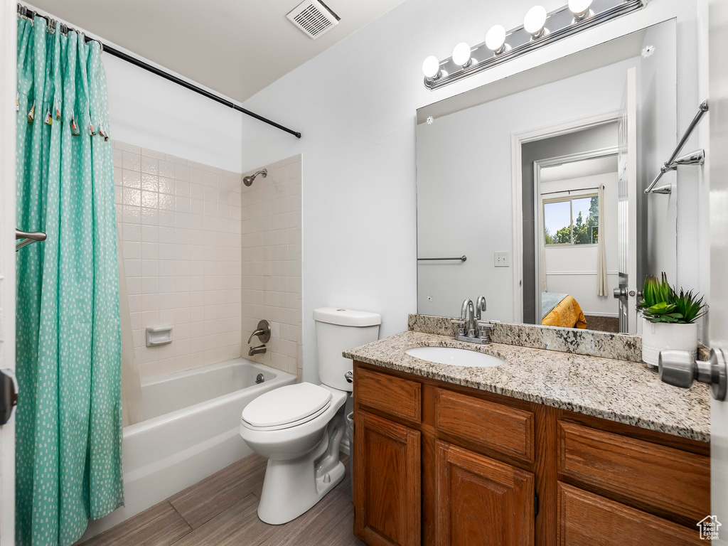 Bathroom with toilet, visible vents, shower / bath combination with curtain, and vanity