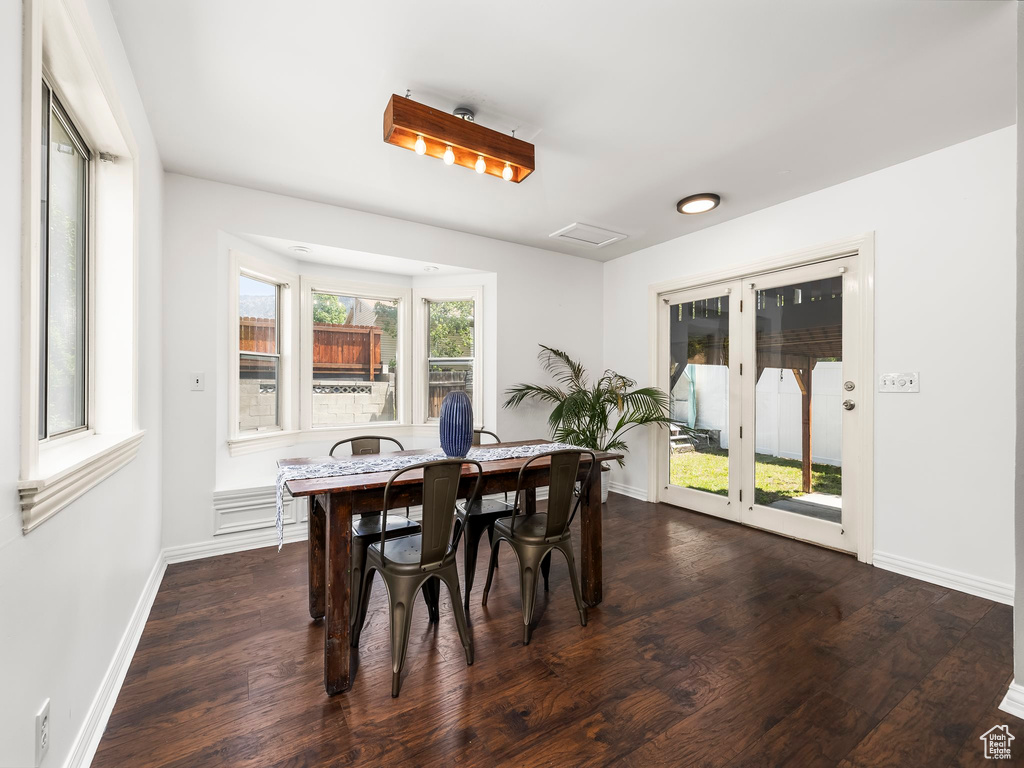 Dining space with dark wood-style flooring and baseboards