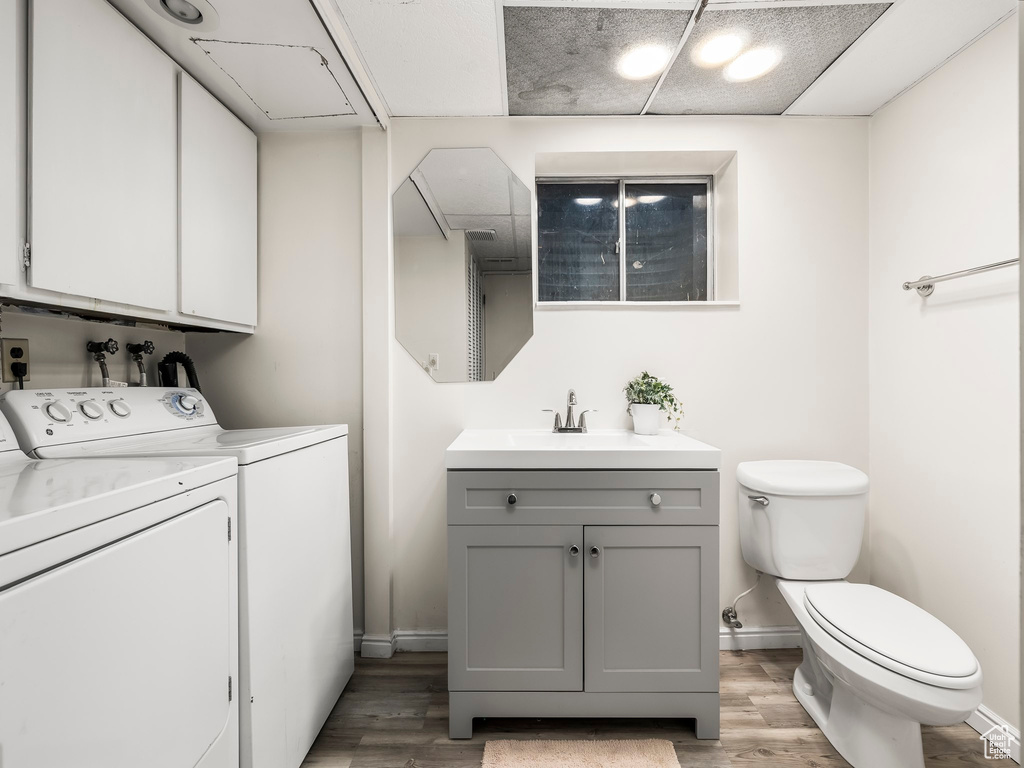 Bathroom with baseboards, toilet, wood finished floors, and washer and clothes dryer