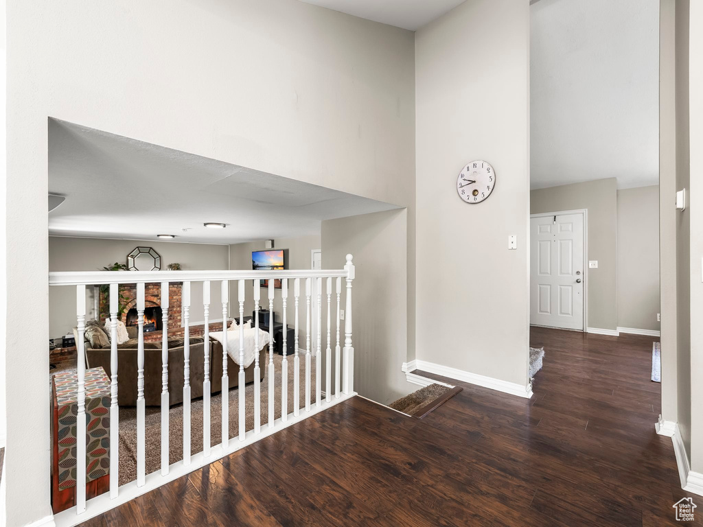 Hallway with baseboards, wood finished floors, and a towering ceiling