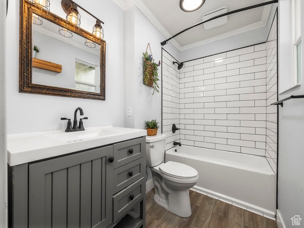 Full bathroom with shower / bathing tub combination, wood finished floors, vanity, toilet, and ornamental molding