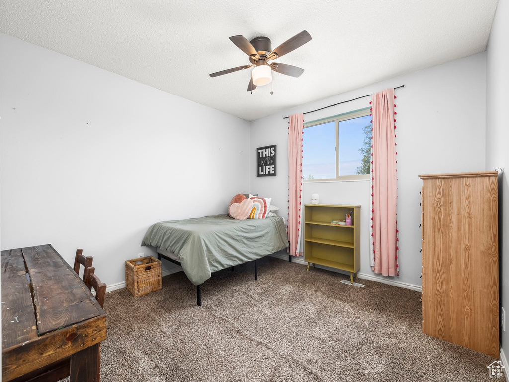 Carpeted bedroom with a ceiling fan and baseboards
