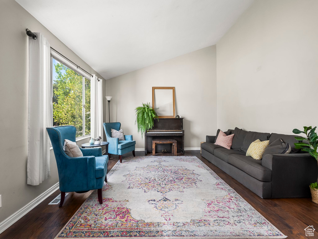 Living room with wood finished floors, baseboards, and lofted ceiling