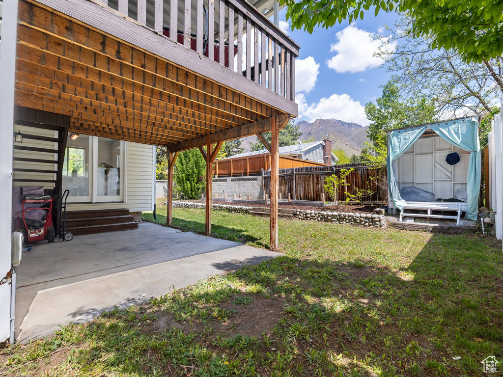 View of yard featuring a fenced backyard, a shed, entry steps, a mountain view, and an outbuilding
