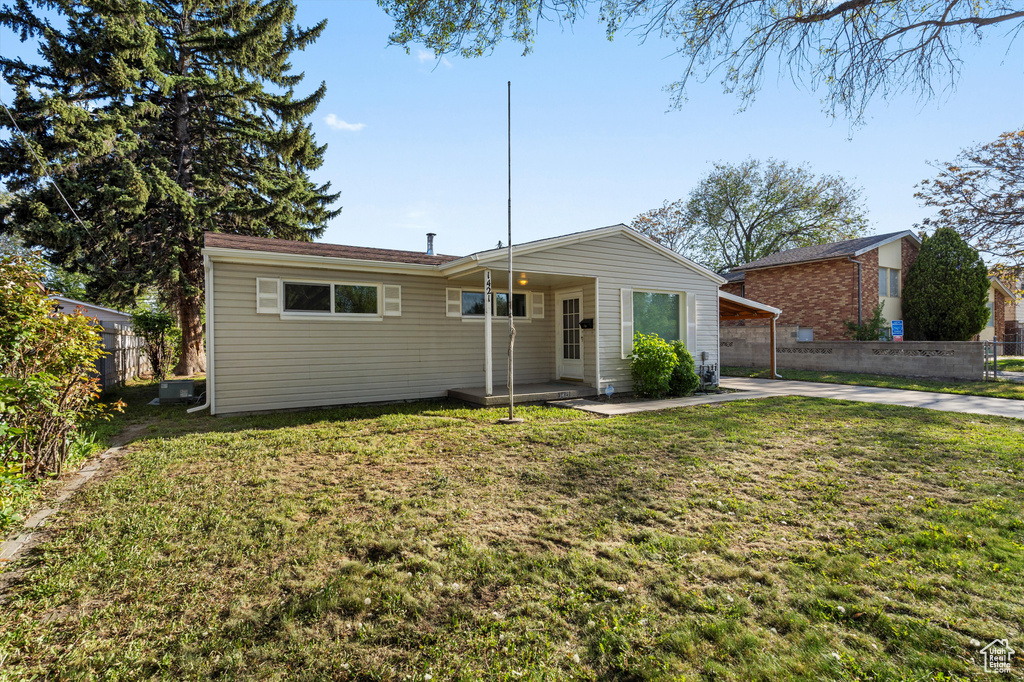 View of front facade featuring a patio, fence, a front yard, and a carport
