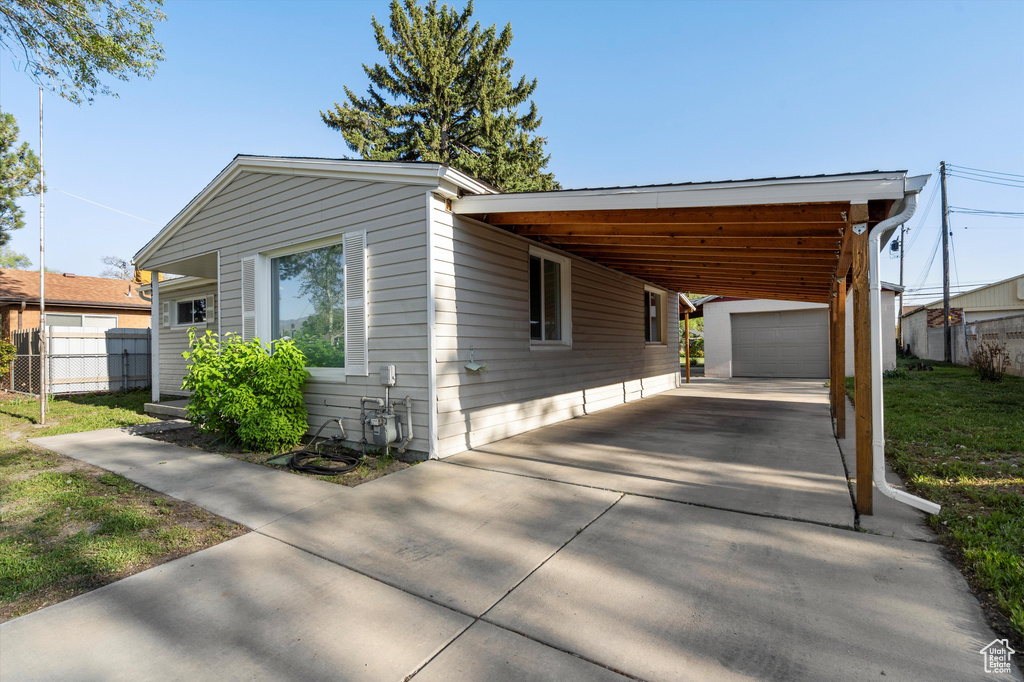 Manufactured / mobile home with fence, driveway, an outdoor structure, and an attached carport