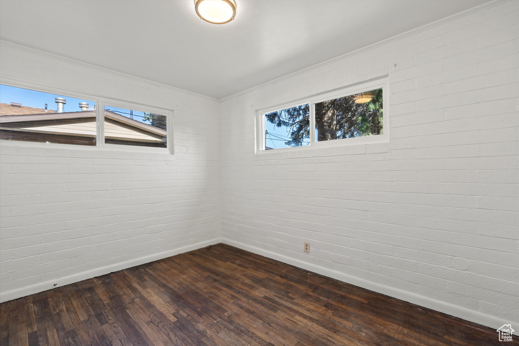 Empty room with baseboards, dark wood-style floors, and ornamental molding