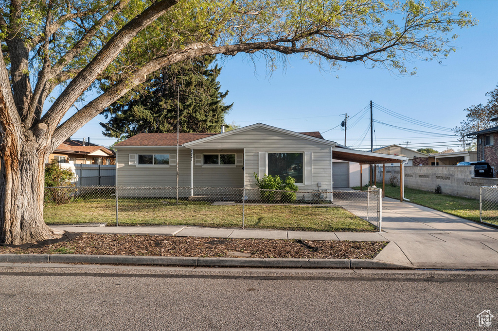 View of front facade with concrete driveway, a fenced front yard, and a front lawn