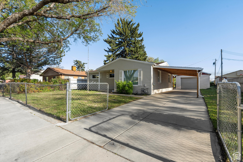View of front of property with fence private yard, driveway, a front yard, an outbuilding, and a carport