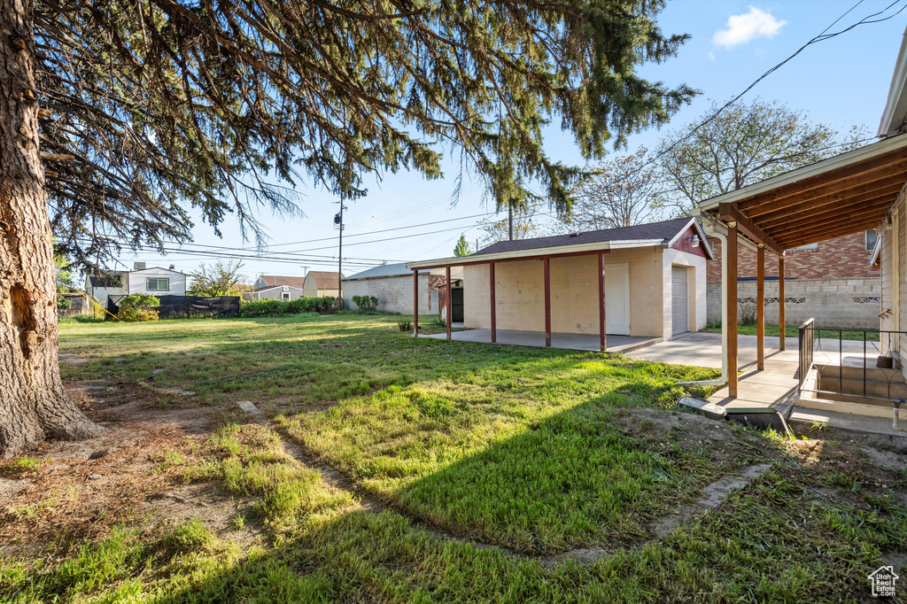 View of yard featuring an outdoor structure, fence, and a patio