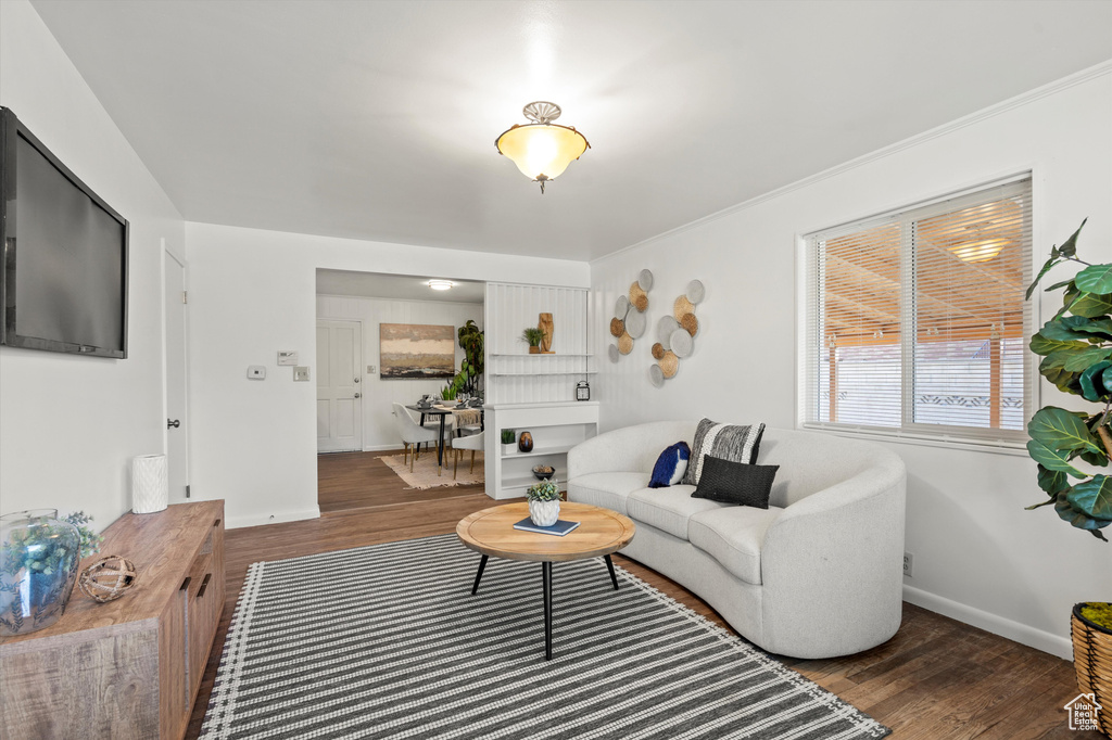 Living room featuring baseboards, ornamental molding, and wood finished floors