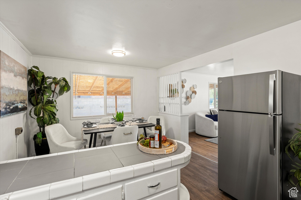 Kitchen with dark wood-style flooring, tile counters, freestanding refrigerator, open floor plan, and a wealth of natural light