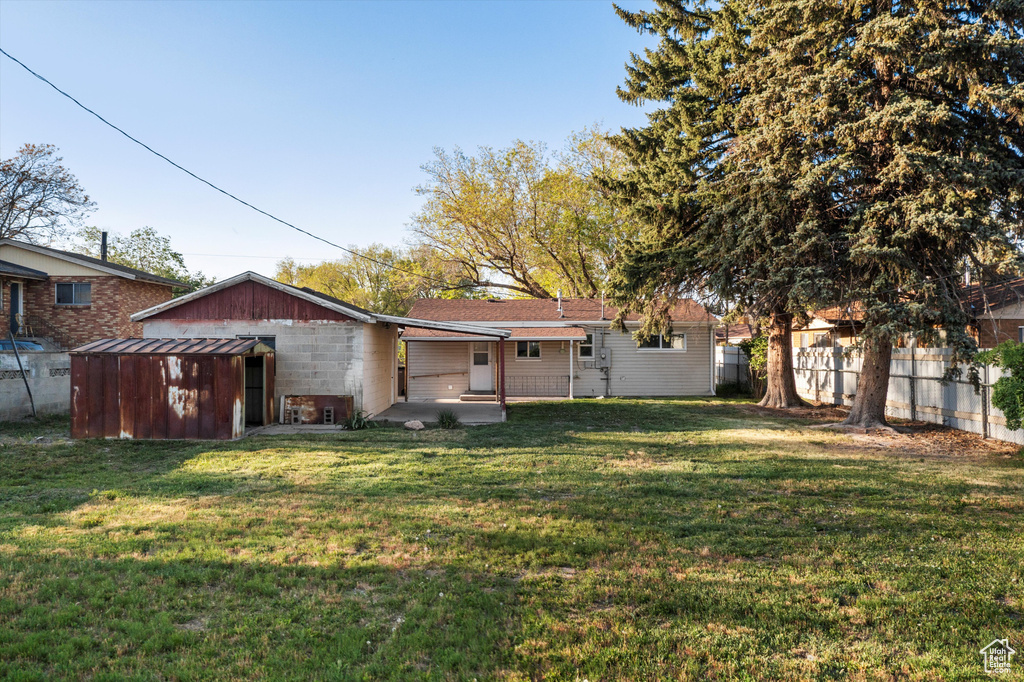Rear view of property with a yard, fence, and a patio area