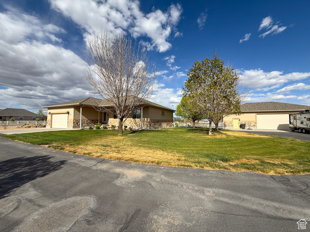 View of front of property with stucco siding, driveway, a front yard, and a garage