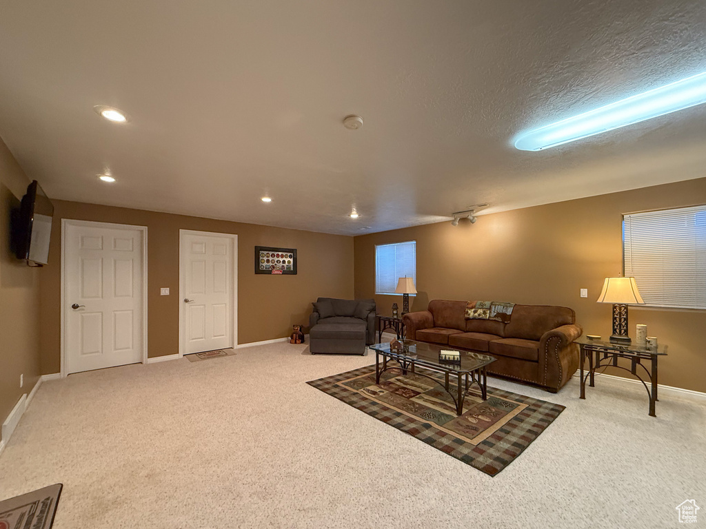 Carpeted living area with recessed lighting and baseboards