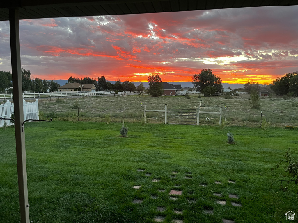Yard at dusk with fence and a rural view