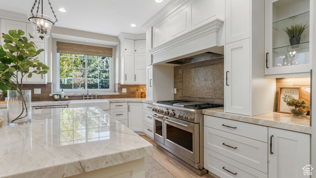 Kitchen featuring a sink, recessed lighting, white cabinetry, and range with two ovens