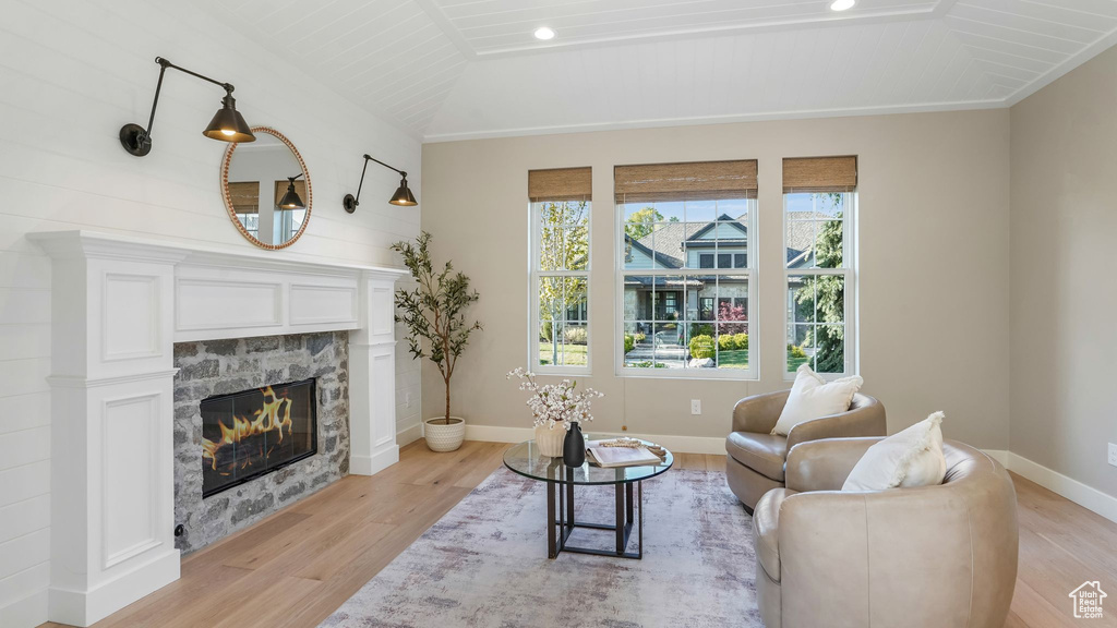 Living area featuring baseboards, a fireplace, vaulted ceiling, and light wood finished floors