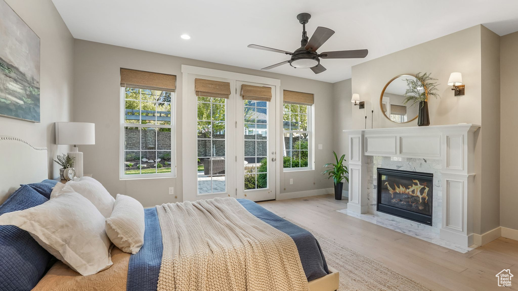 Bedroom featuring baseboards, light wood-style flooring, a fireplace, and access to exterior