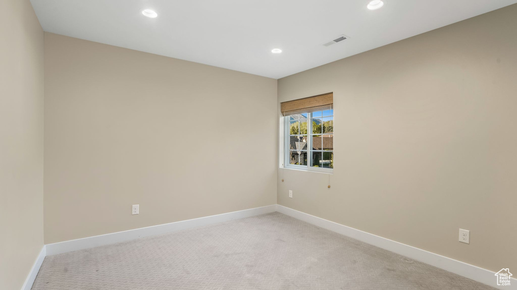 Empty room featuring light colored carpet, recessed lighting, and visible vents