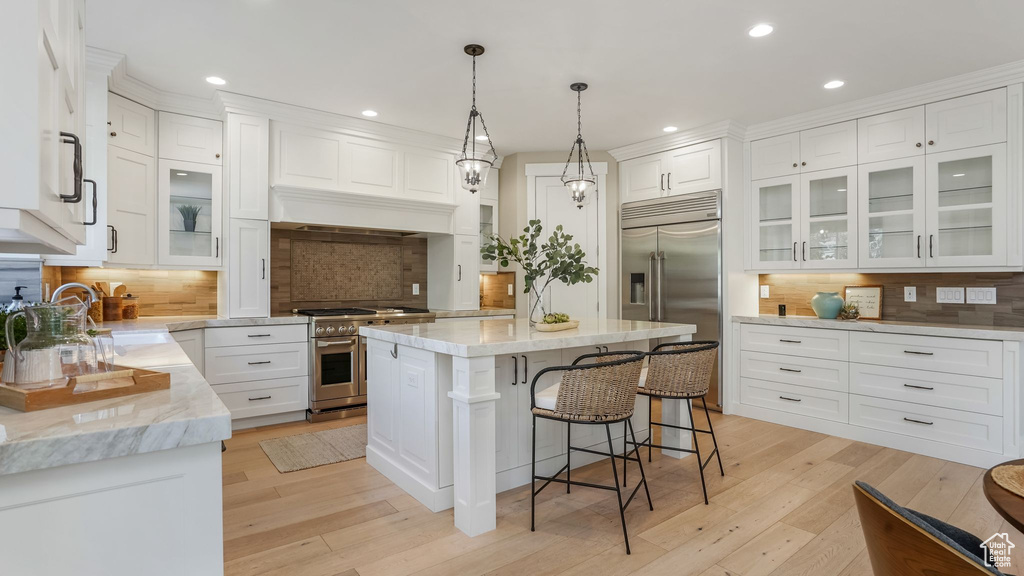 Kitchen featuring recessed lighting, white cabinetry, tasteful backsplash, and premium appliances