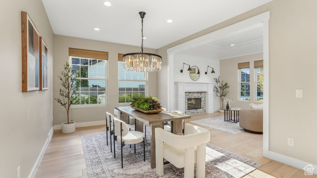 Dining area with a notable chandelier, light wood finished floors, a glass covered fireplace, recessed lighting, and baseboards