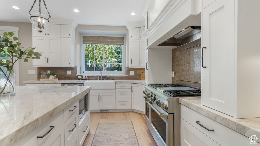 Kitchen with a sink, premium range hood, recessed lighting, and double oven range