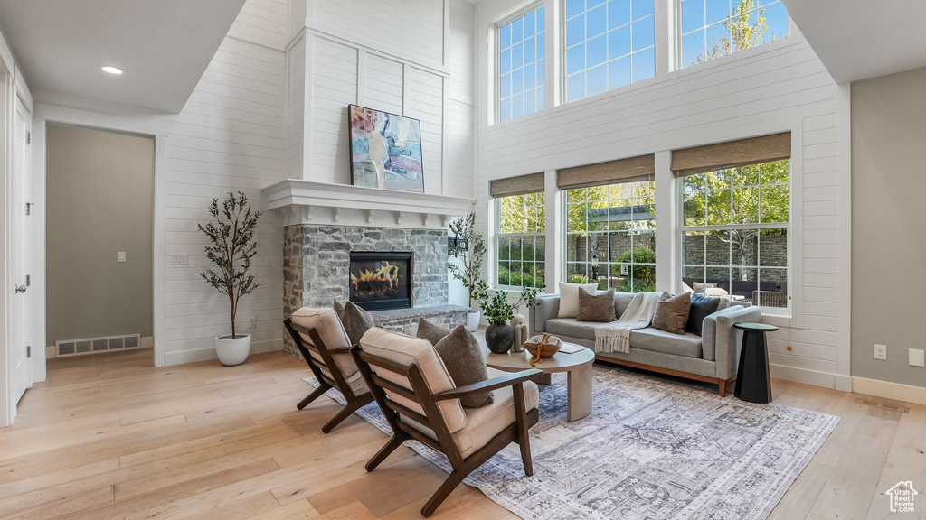 Living room with a fireplace, hardwood / wood-style floors, baseboards, a towering ceiling, and visible vents