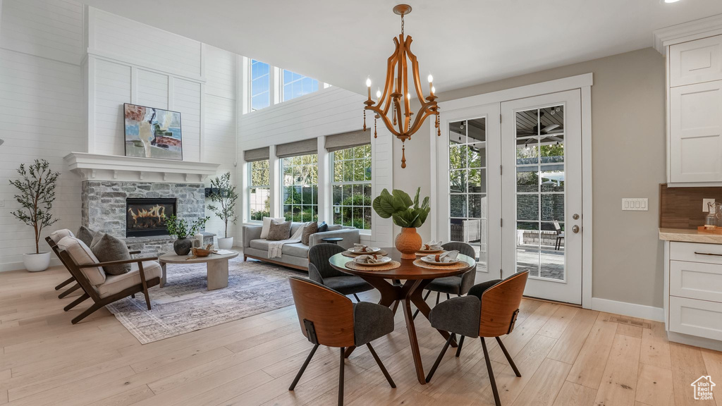 Dining room with baseboards, a fireplace, light wood-style flooring, and a notable chandelier