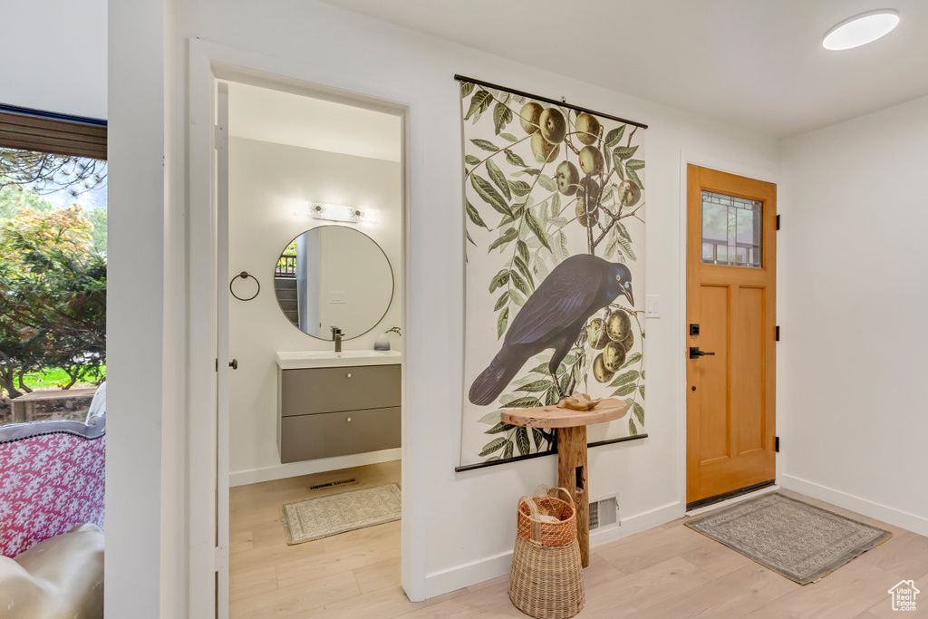 Foyer with baseboards, wood finished floors, and visible vents