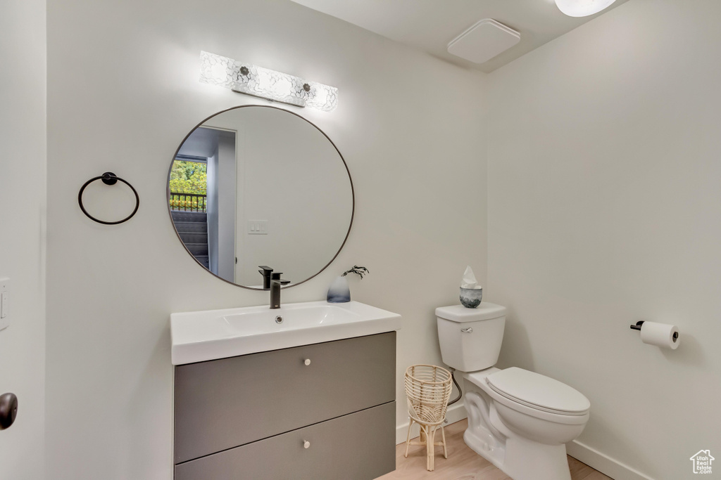 Bathroom with vanity, baseboards, toilet, and wood finished floors