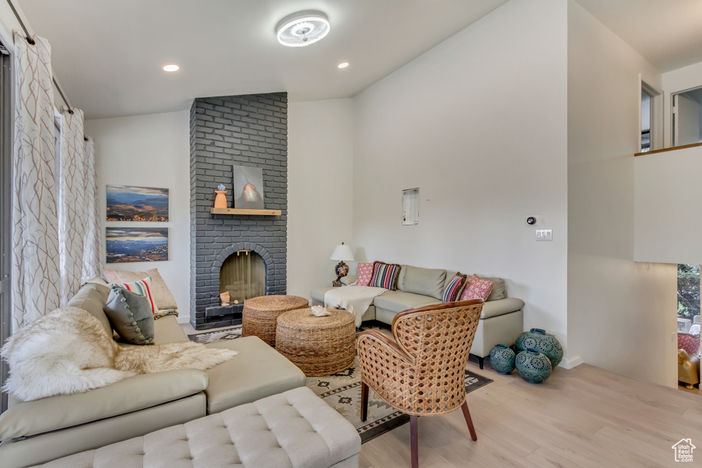 Living room featuring a fireplace, recessed lighting, baseboards, wood finished floors, and lofted ceiling
