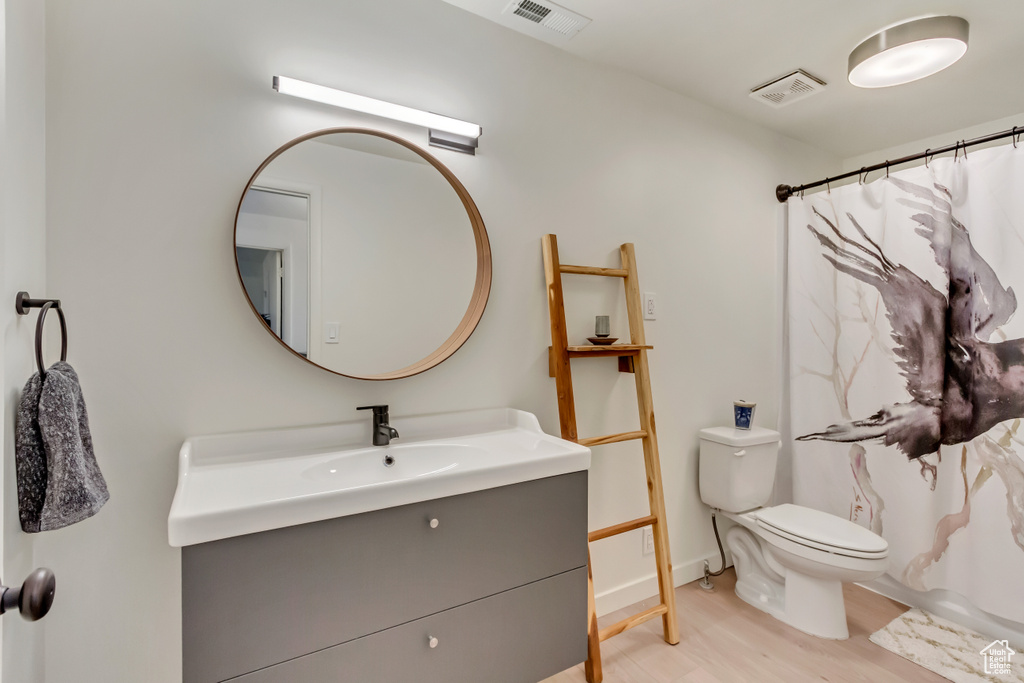 Full bathroom featuring toilet, visible vents, wood finished floors, and vanity