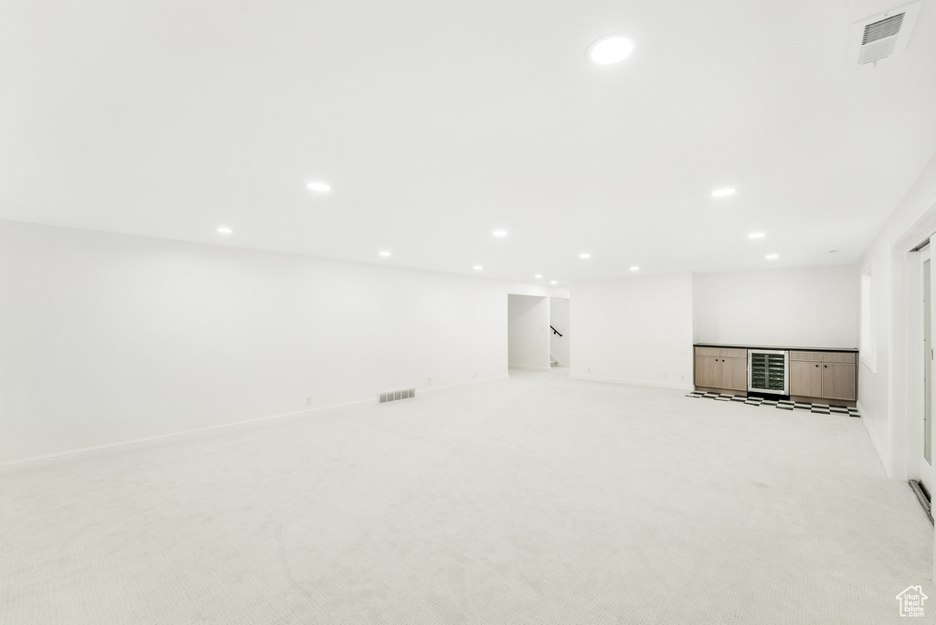 Below grade area featuring light carpet, beverage cooler, recessed lighting, baseboards, and visible vents
