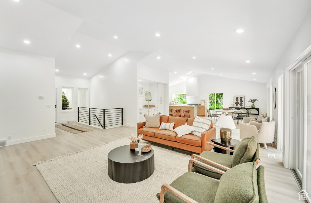 Living area featuring high vaulted ceiling, baseboards, and light wood-type flooring